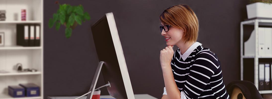 Junge Frau sitzt vor einem Bildschirm mit Benutzeroberfläche von Libelle DataMasking